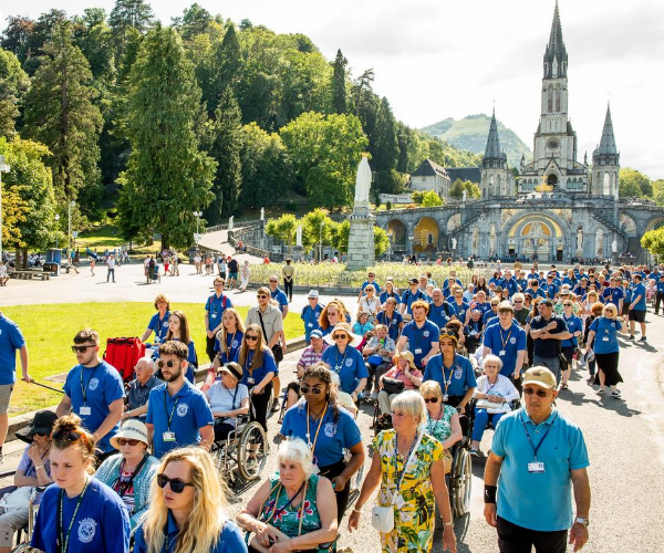 Image shows hundreds of diocesan pilgrims processing in blue t-shirts in front of the basilica