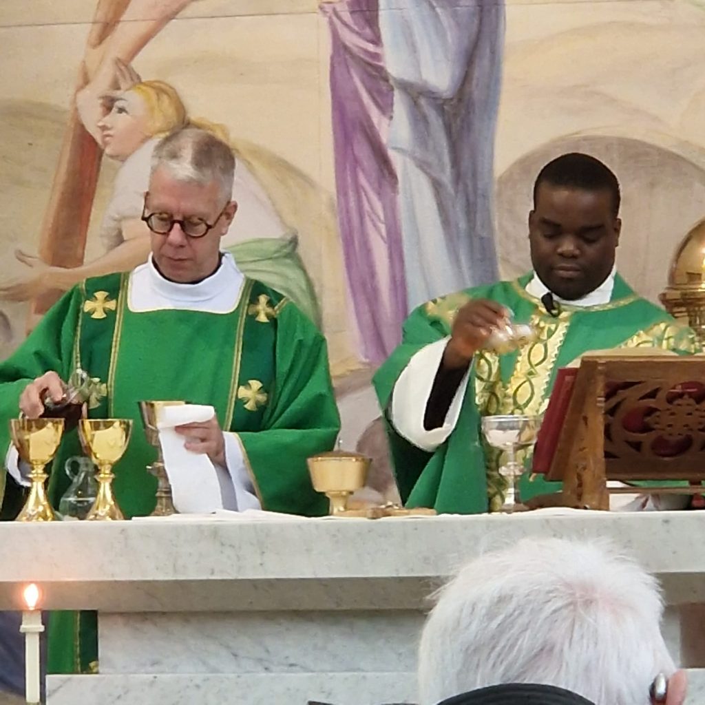 Deacon Paul in green vestments assists at the altar during Mass