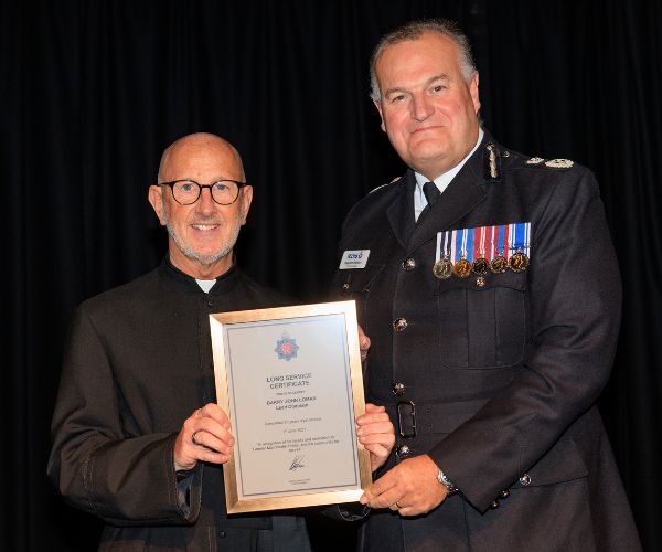 Fr Barry (left) stands with Chief Constable Stephen Watson (right) holding his Long Service Certificate