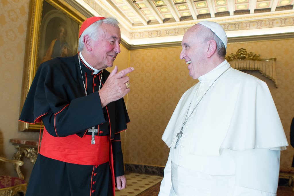 Cardinal Nichols (left) laughs with Pope Francis (right) in an ornate room 