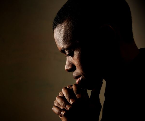 A young man with hands together in prayer