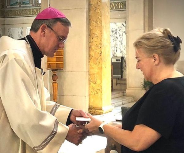 Bishop John presents a woman with Synod Member certificate and resources