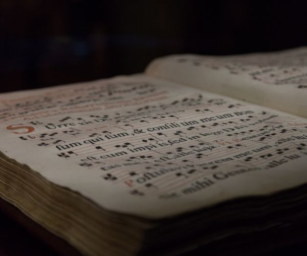 A book of Gregorian Chant notation lies open against a dark background