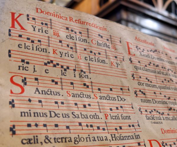 A photo showing music manuscript with Gregorian chant written on with parts of the Mass written in Latin