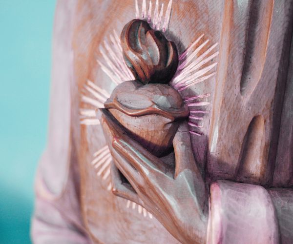Close up of a statue of the Sacred Heart, focusing on Jesus' hand touching his heart