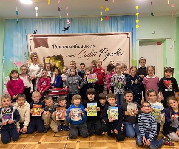 Children in own clothes gather together holding books for a photo with their new electrical generator, provided by donations from a Mercy Brothers fundraiser