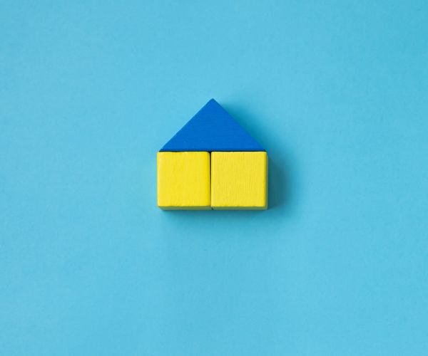 Light blue background with a house made of blue and yellow blocks to represent Ukraine